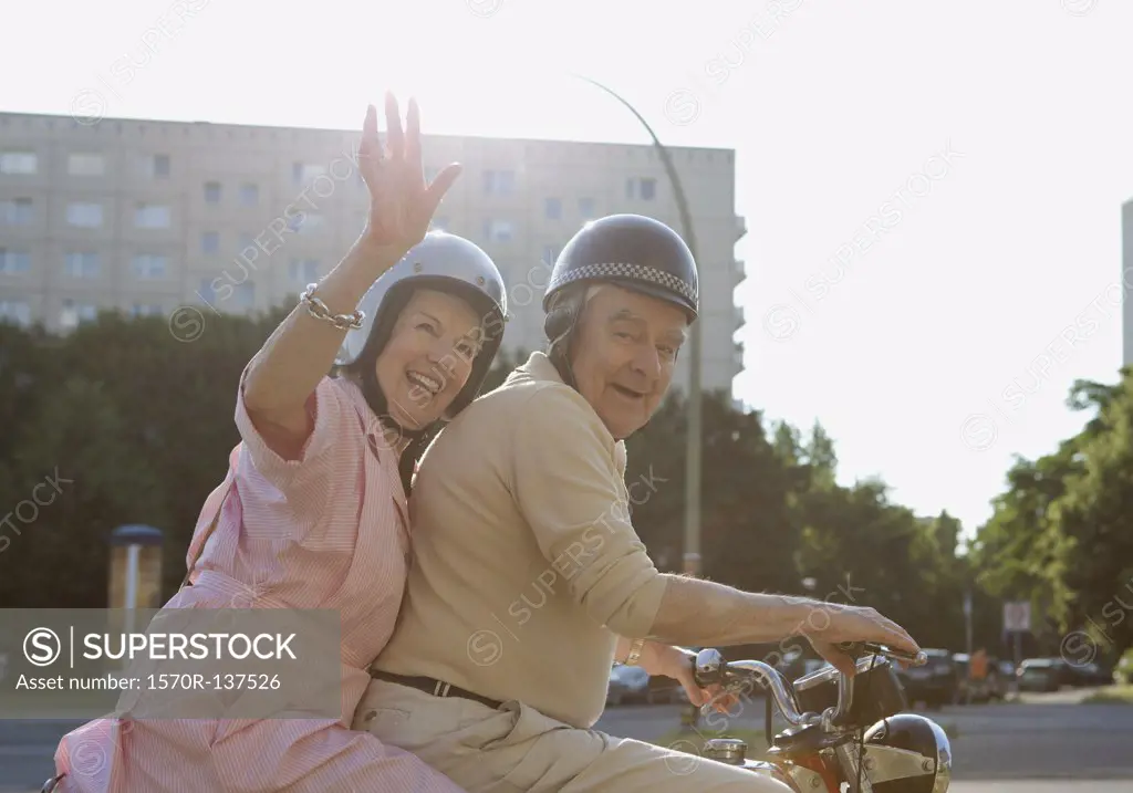 Senior couple happy on motorbike as woman waves