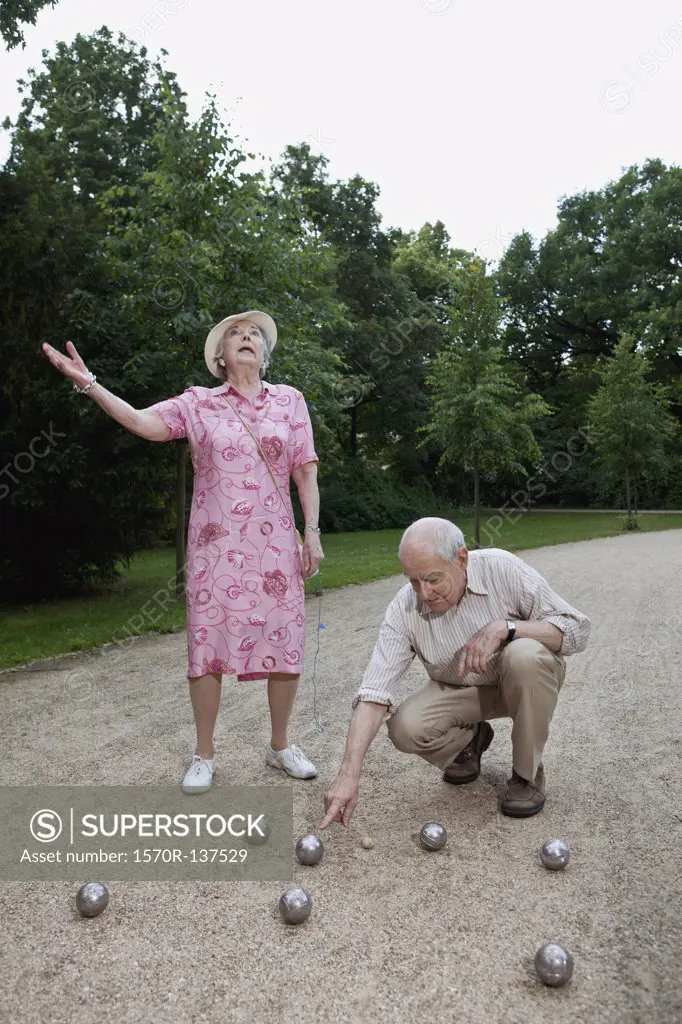 Senior man and woman have dispute playing boules in the park