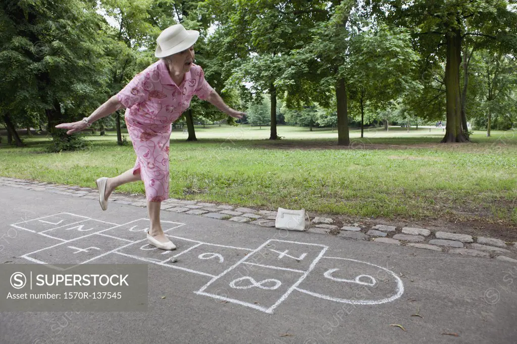Senior woman plays hopscotch trying to keep her balance