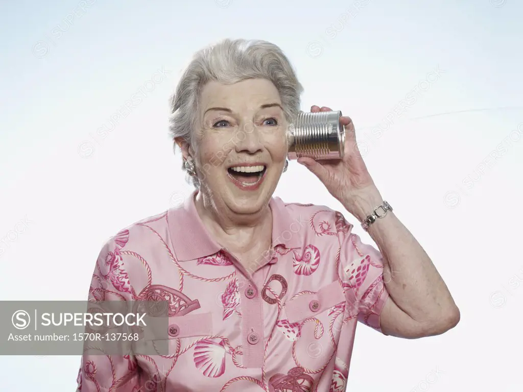 Senior woman comically listens to tin can phone