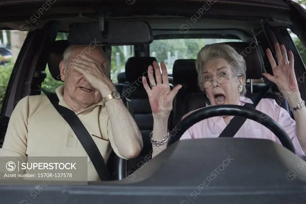Senior woman having trouble learning to drive as man in passenger seat despairs