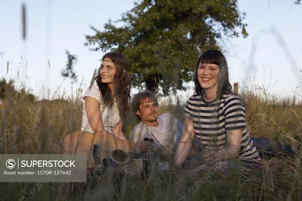 Three friends amongst the timothy grass with wine and guitar