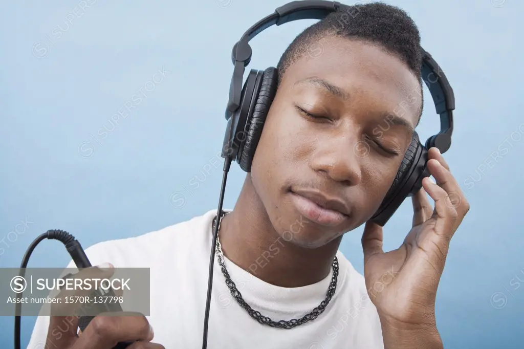 A young man listening to music with headphones, eyes closed