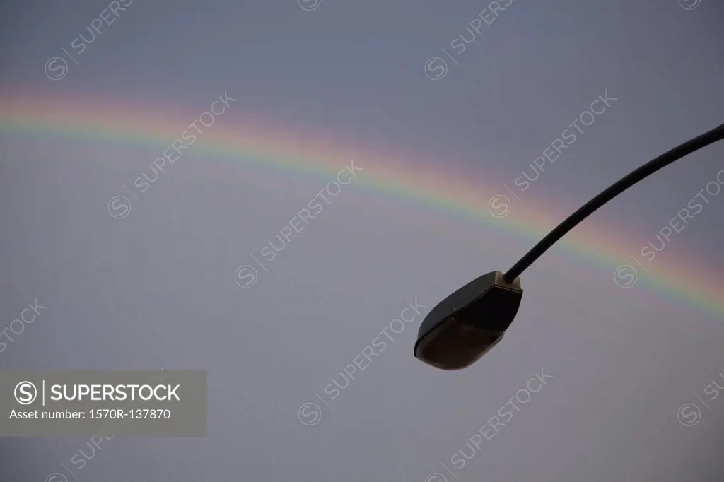 A rainbow in back of a silhouetted street lamp