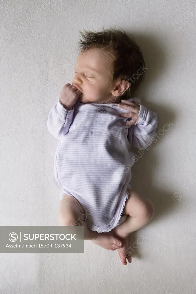A sleeping newborn sucking on her fist