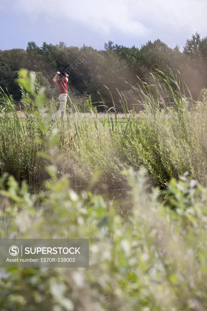 A female golfer teeing off, focus on background
