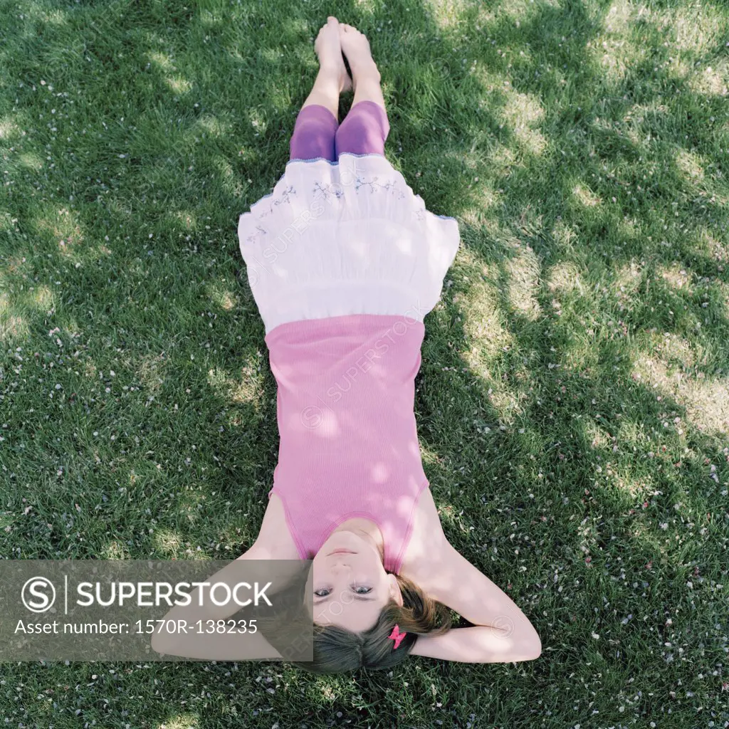 A girl lying in grass with hands behind head, upside down view