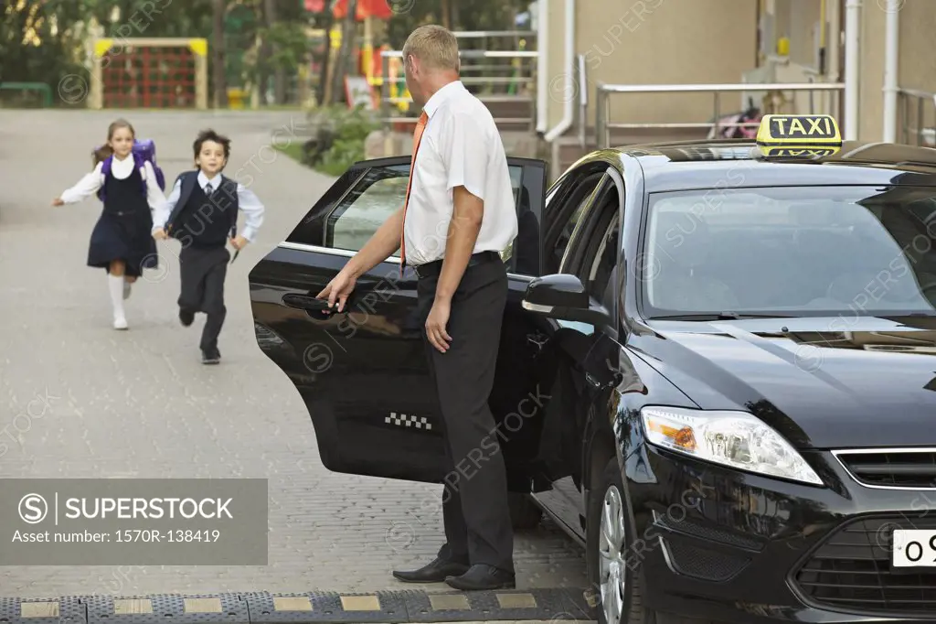 Two children in school uniforms running towards black cab