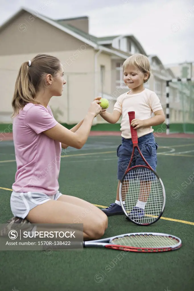 A mother teaching her young son tennis