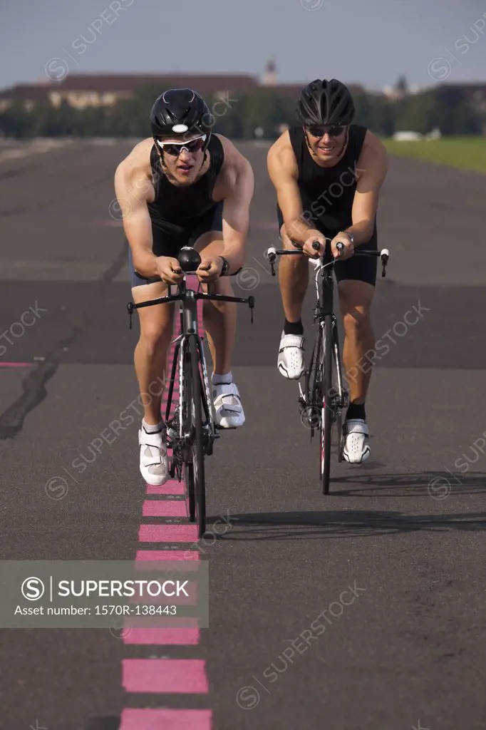 Two cyclists on racing bicycles cycling on a marked road