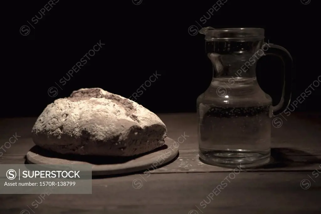 A loaf of bread and a jug of water on a table