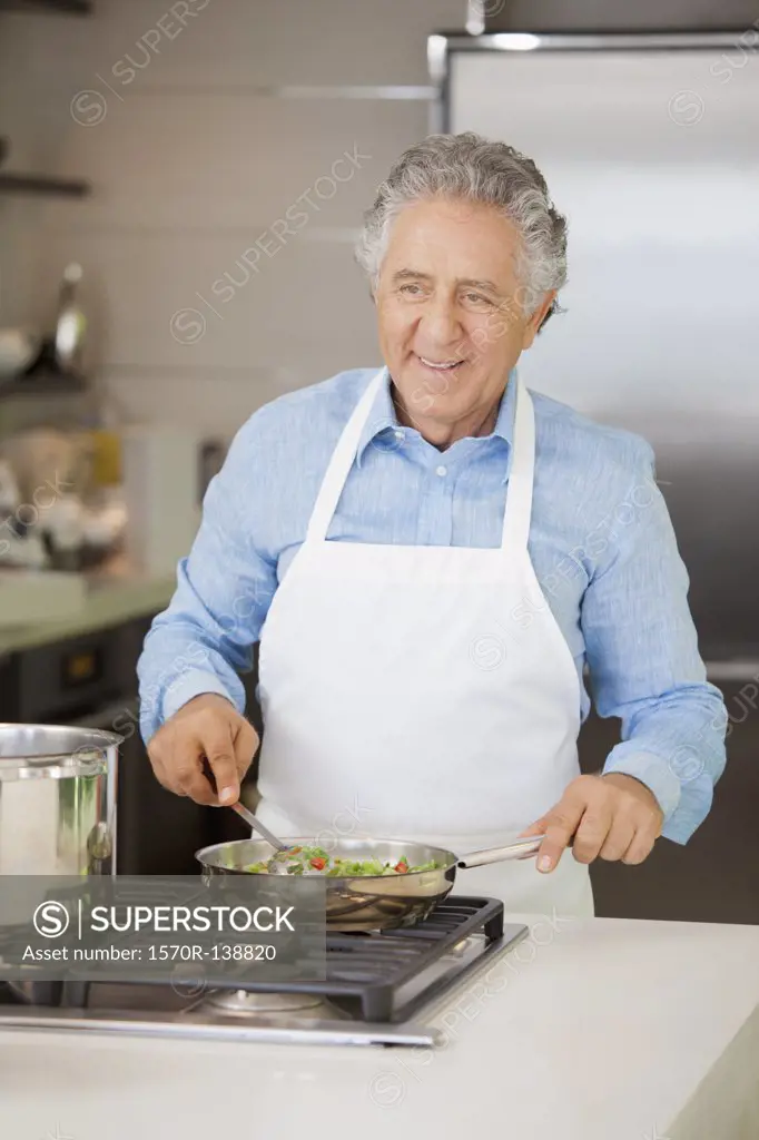 A cheerful retired man cooking vegetables in a pan