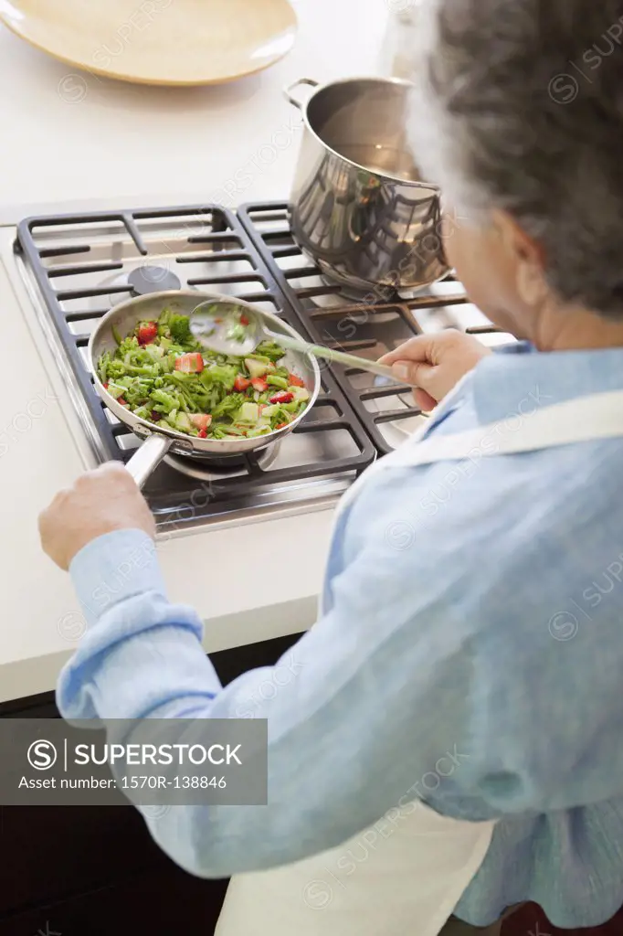 Over the shoulder view of a senior man cooking vegetables