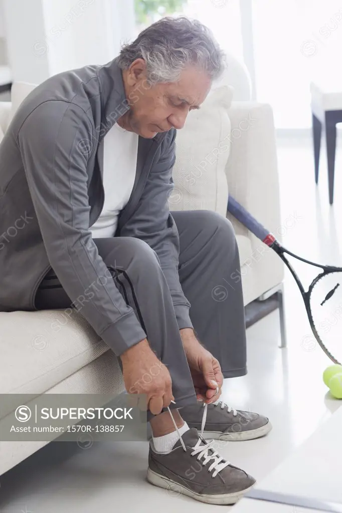 A senior man tying his shoelaces, preparing to play tennis