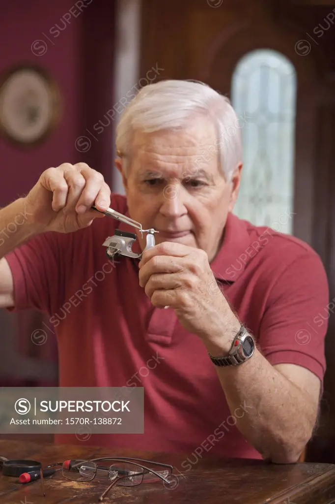 A man using tweezers on a miniature toy motor scooter
