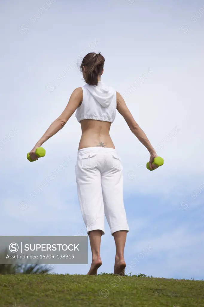 Girl in field lifting dumbbells
