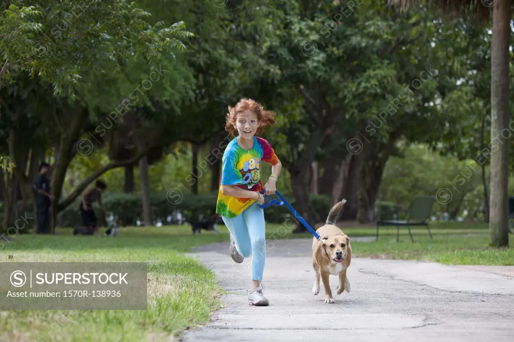 Girl running with dog through park