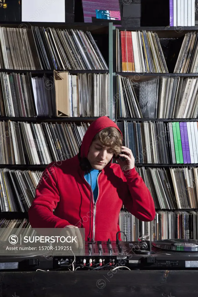 A young man using decks and a sound mixer at a record store