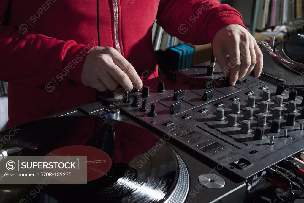 A DJ adjusting knobs on a sounder mixer, detail of hands