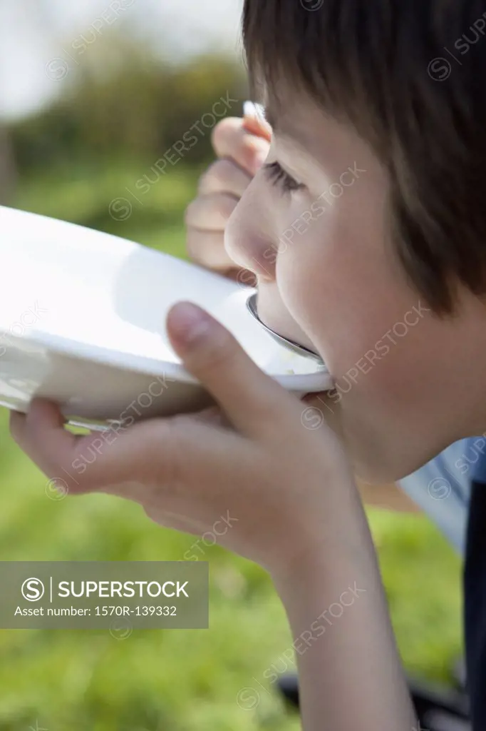 A young boy eating out of a bowl with a spoon