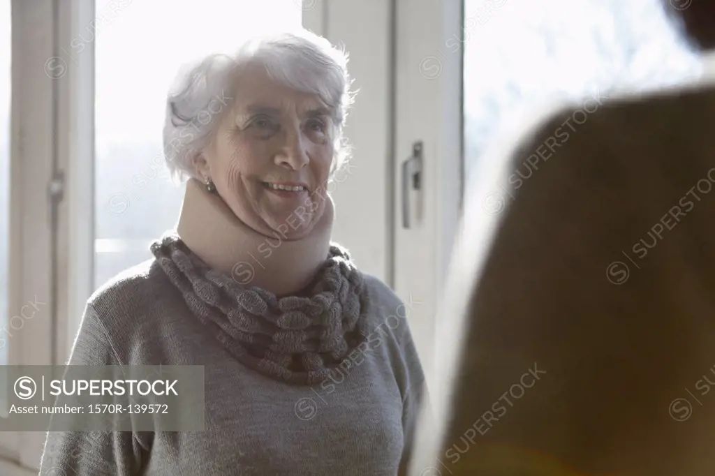 A smiling senior woman wearing a neck brace