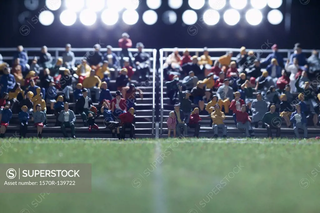 The center field of a miniature soccer field, spectator figurines in background