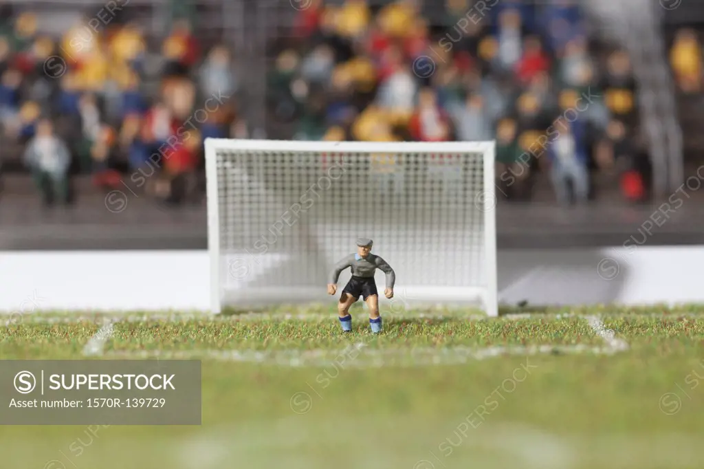A miniature soccer goalie figurine guarding the goal post