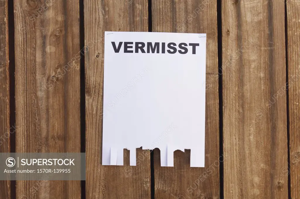 A flyer posted on a wooden fence with the German word for missing on it