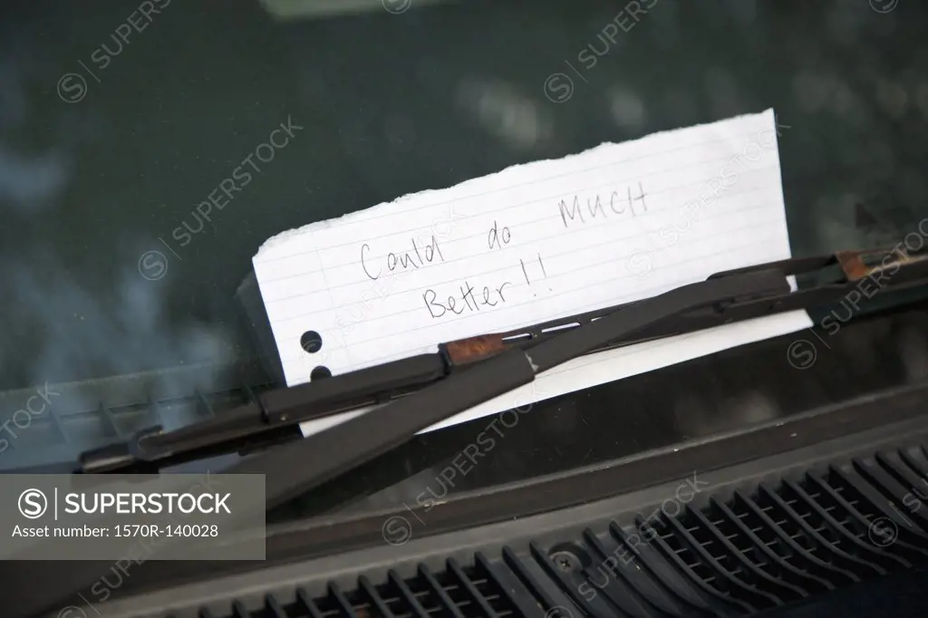 A handwritten note tucked behind a windshield wiper