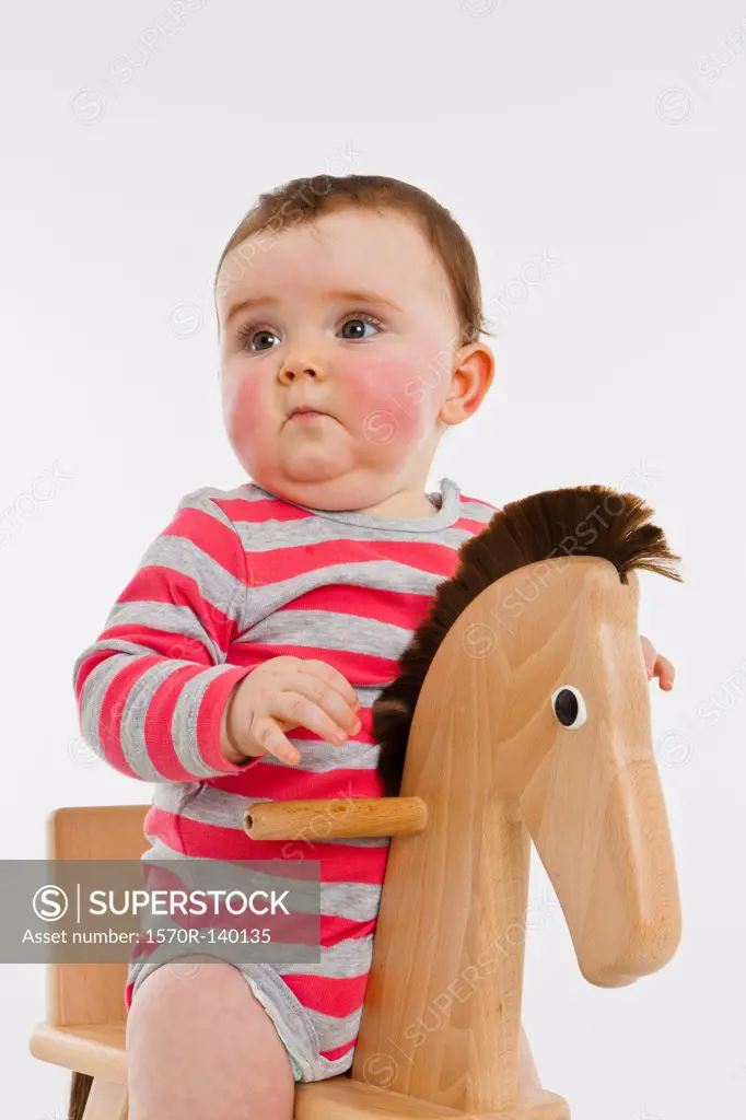 A baby girl on a rocking horse