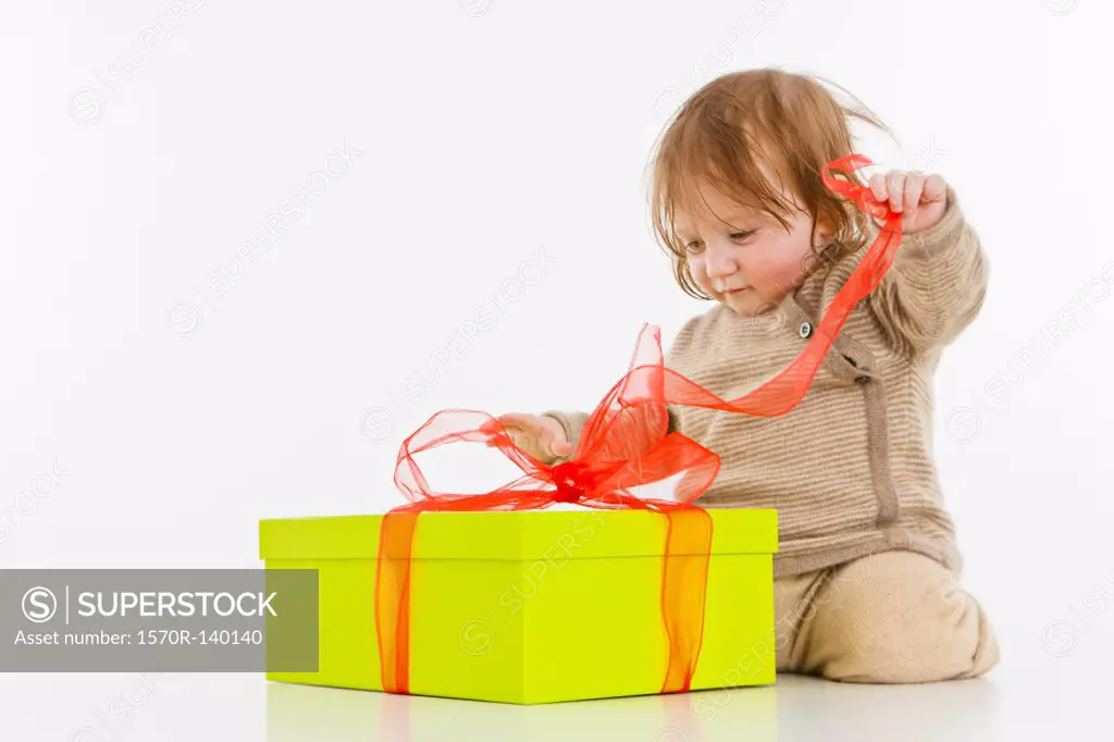 A baby girl unwrapping a present