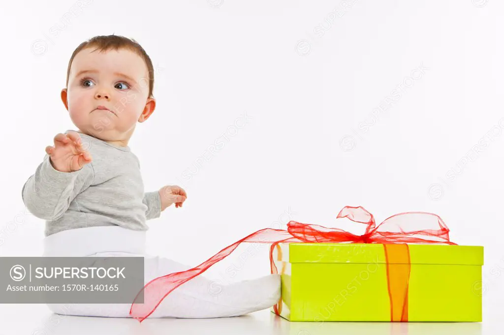 A baby girl sitting with a present