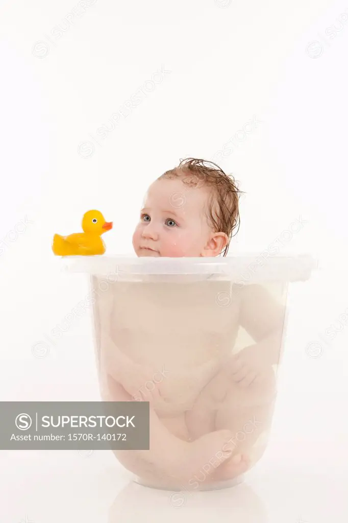 A baby girl sitting in a bucket of water