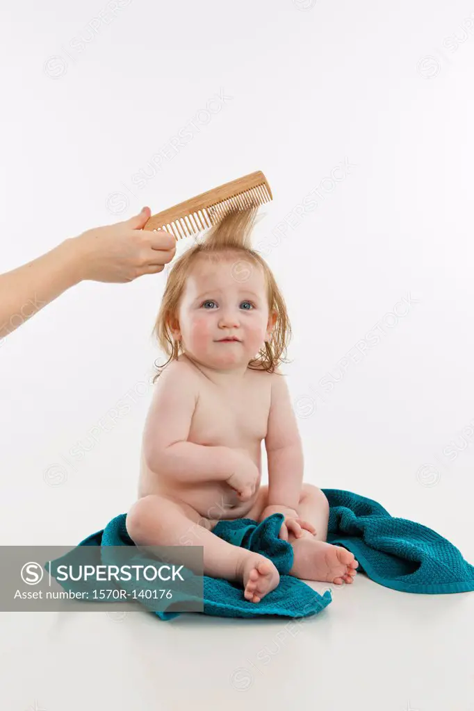 A baby girl having her hair combed
