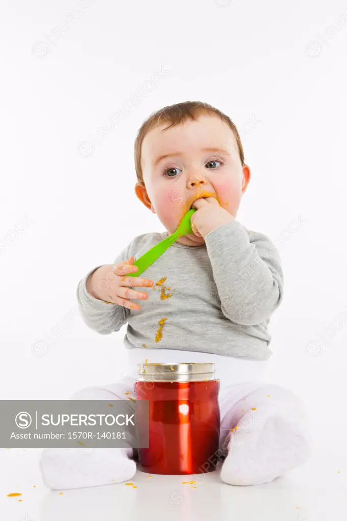 A baby eating food from a container