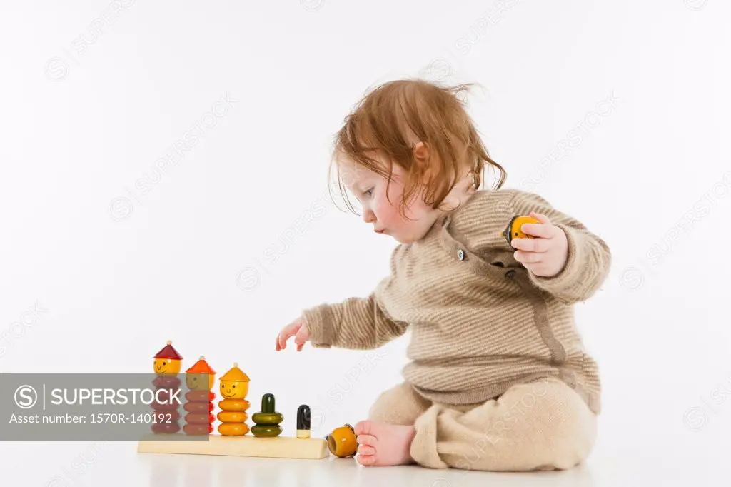 A baby girl playing with a wooden stacking toy