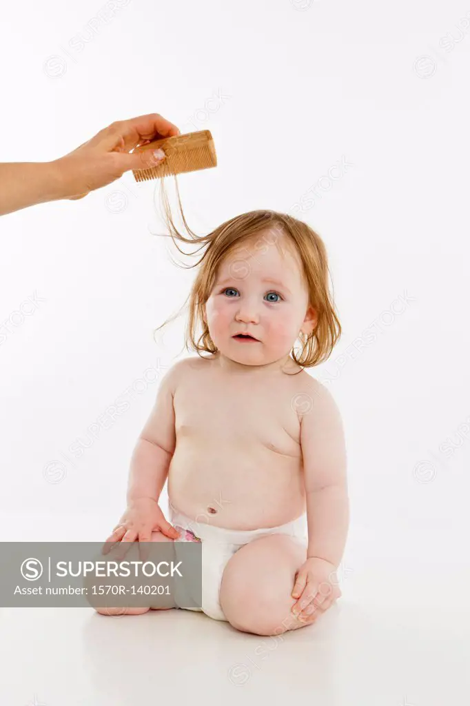 A baby girl having her hair combed