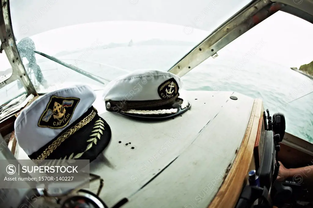 Two captain's hats resting on the dashboard of a motorboat, Avacha Bay, Russia