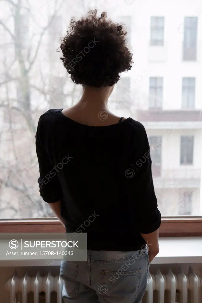 Rear view of a woman looking through a window