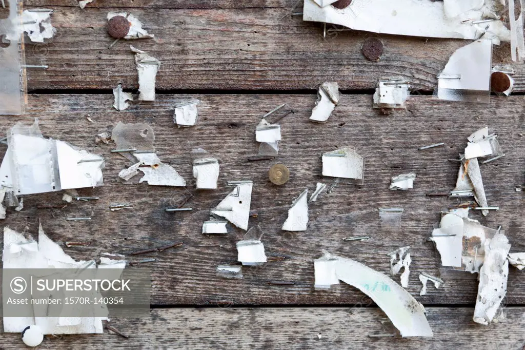 Detail of staples, thumbtacks and ripped paper on a wooden wall