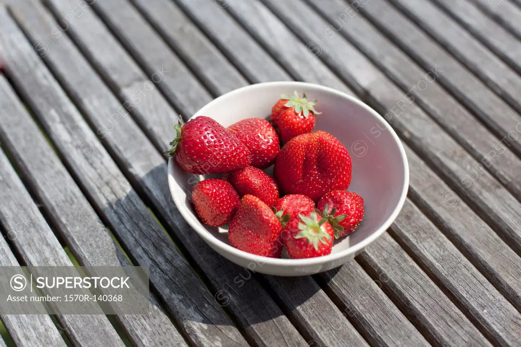 A bowl of strawberries on an outdoor table