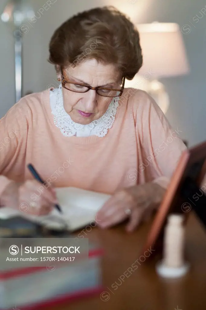 A senior woman writing in a note book
