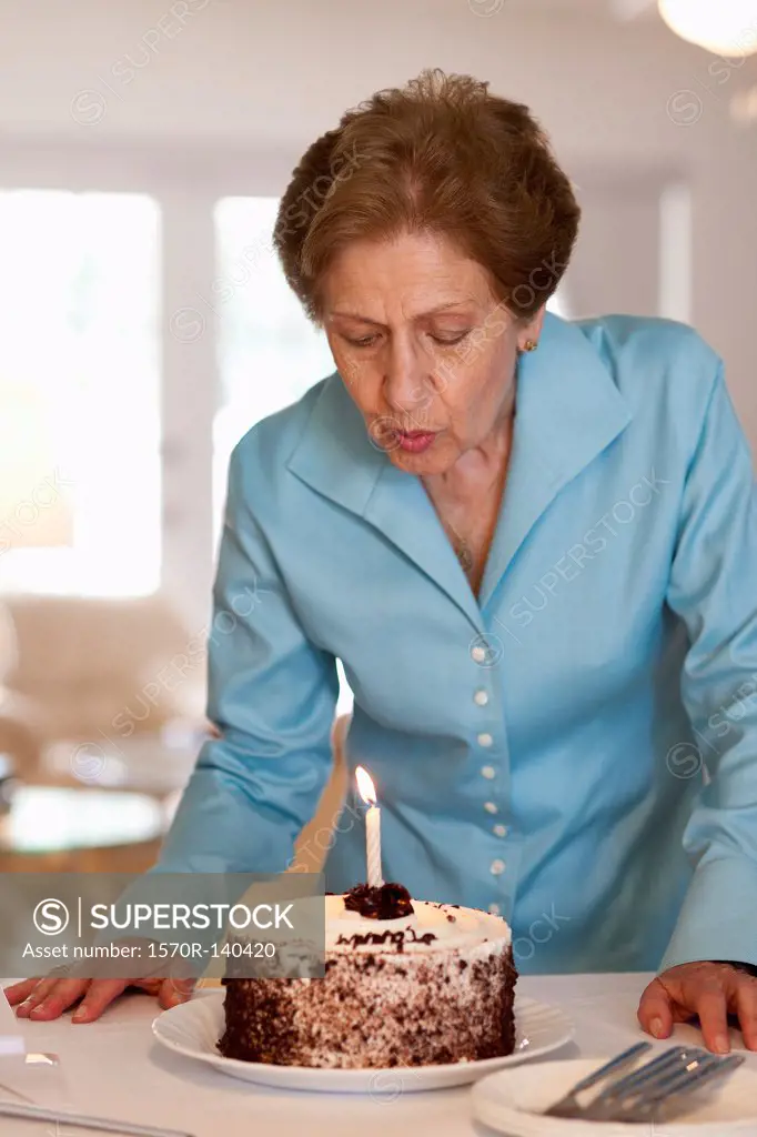 A senior woman blowing out a candle on a cake