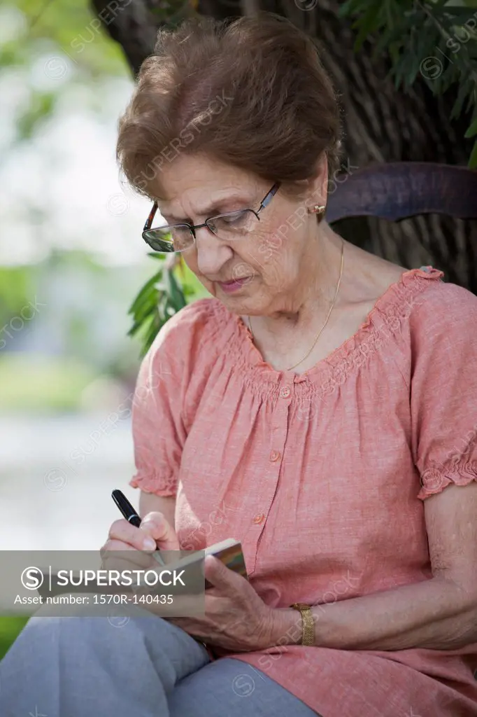 A senior woman writing in a book