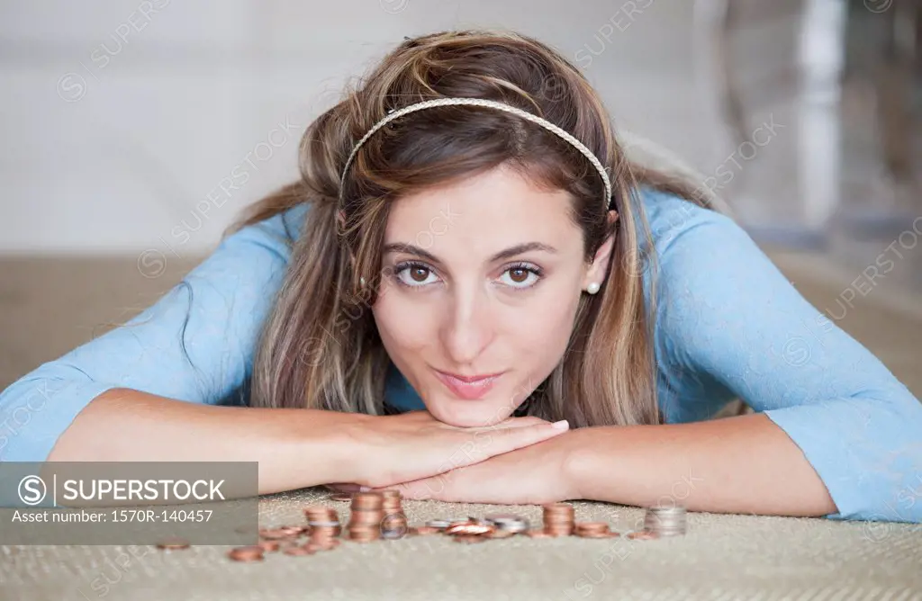 A woman lying on a floor with stacks of US coins
