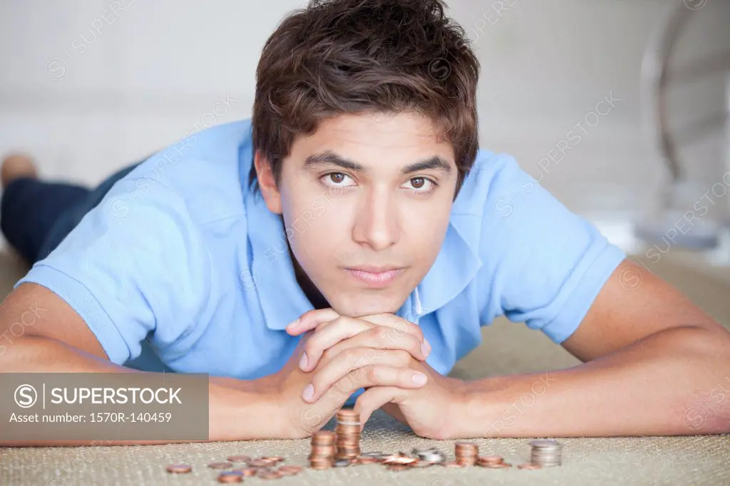 A serious man lying on the floor near stacks of coin