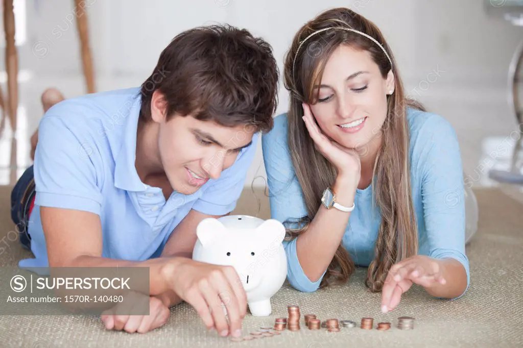 A young cheerful couple counting coins on the floor