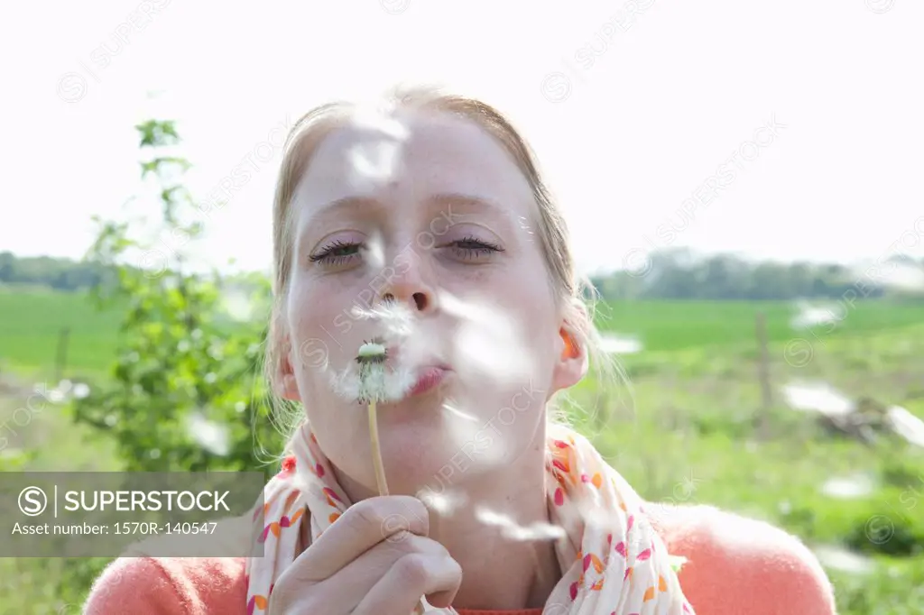 A woman blowing on a dandelion, close-up