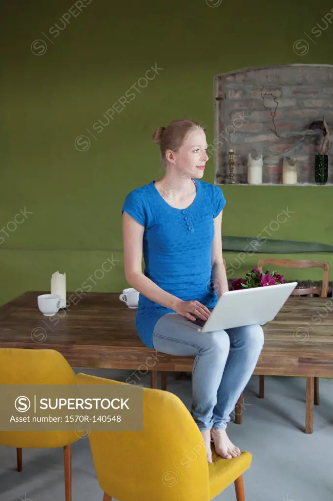A woman sitting on her dining table using a laptop