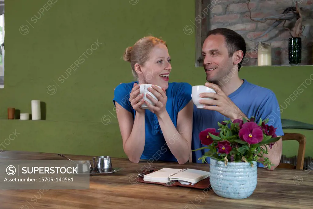 A couple sitting at a dining table with a personal organizer, talking excitedly